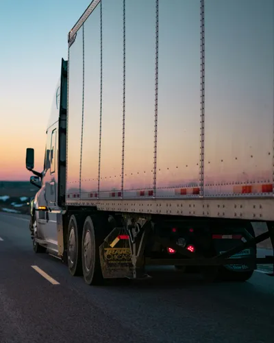 An articulated truck and trailer on an open highway at dusk.